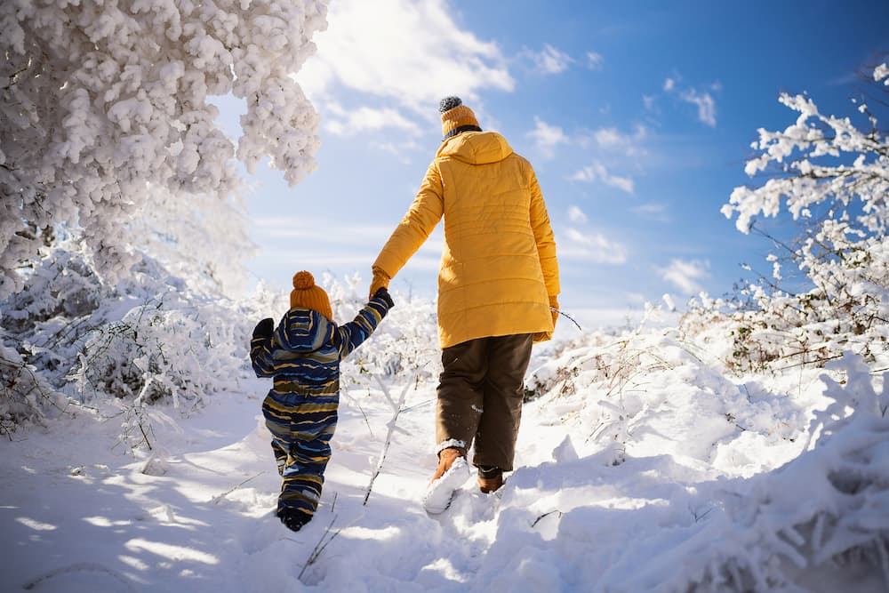 Wintersport: kind met mama wandelen tussen de witte bomen